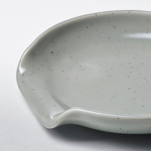 Small, light gray stoneware spoon rest with subtle speckled pattern, designed to prevent kitchen utensil spills.