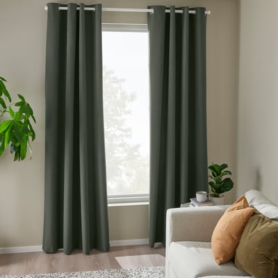 Dark green block-out curtains with eyelets frame large window, complementing cosy beige couch and adding a peaceful ambiance to the room.