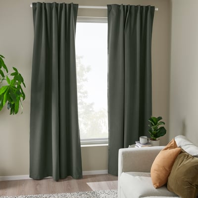 Dark green floor-length ROSENMANDEL block-out curtains hang by a sofa, offering a cozy, light-blocking wool-like texture.