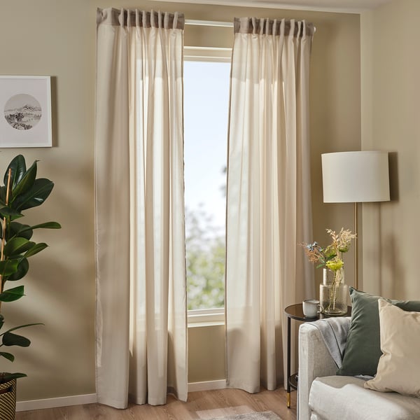 Beige rosenrobina sheer curtain in living room, framed by pillows, lamp, and plant.