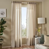 Beige rosenrobina sheer curtain in living room, framed by pillows, lamp, and plant.