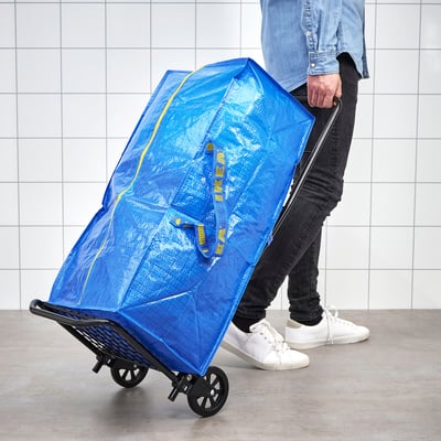 Person pulling large blue bag on wheels.
