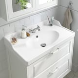 A pristine bathroom sink with chrome faucet and soap dispenser, equipped with water-saving aerator.