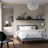 Modern bedroom with SÄBÖVIK bed, globe light, wooden furniture, black chair.
