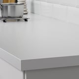 Modern white kitchen counter with silver edge, designed for easy cleaning and durability.