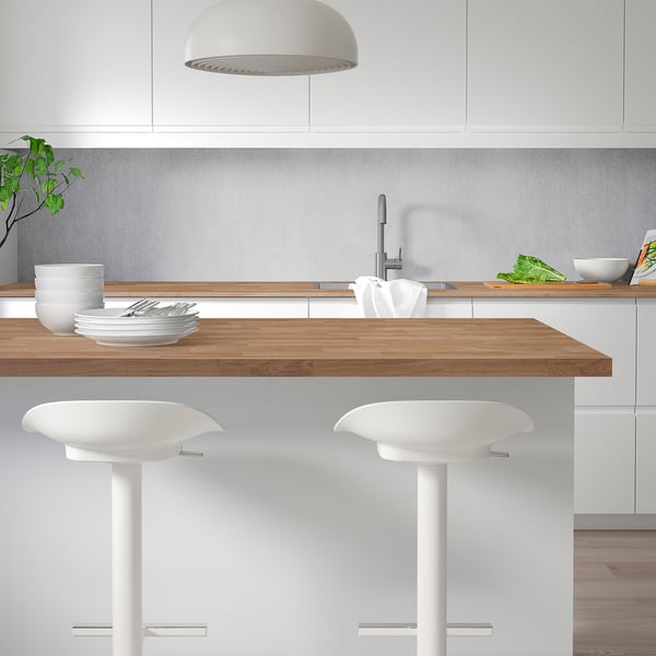Modern kitchen island with SÄLJAN countertop, stools & plant, metallic accents, pendant light.