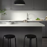 Modern kitchen island in grey & black with SÄLJAN worktop, two black stools and minimalist decor.
