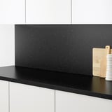 Black speckled kitchen counter with a wooden chopping board and a white utensil holder.