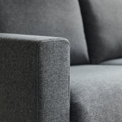 Close-up of a modern, grey upholstered sofas corner, showcasing its clean lines and soft, textured fabric.