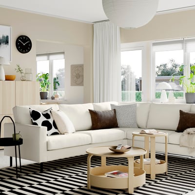 Modern living room with SALTSJÖBADEN sofa, coffee table, large windows, striped rug, planter, clock, pendant light.
