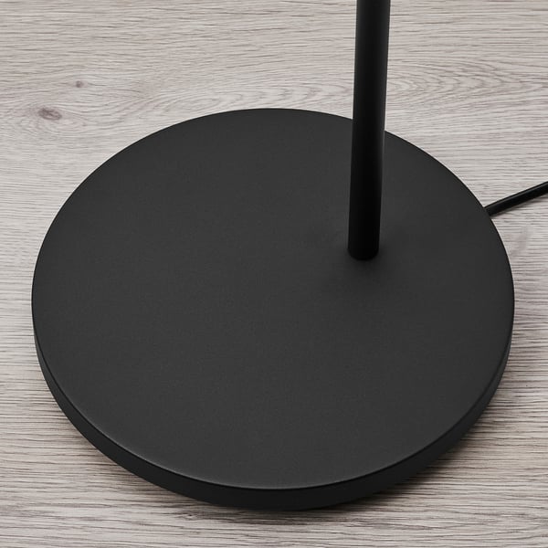 Black floor lamp base on wooden floor, sleek design, sturdy round base with central support pole, quality finish.