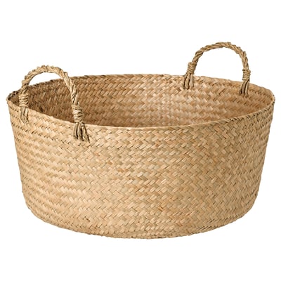 A handmade SANDJORD woven basket. Its beige, circular, and made from sedge material. It two handles for easy carrying.