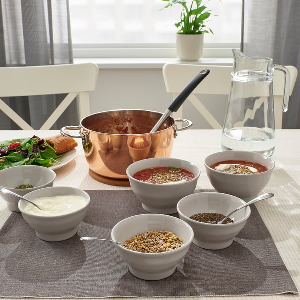 A rustic dining table with soup, sides, and place mats. Character count: 48