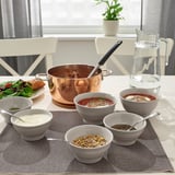 A rustic dining table with soup, sides, and place mats. Character count: 48