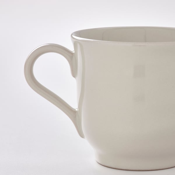 Close-up of a smooth, cream-colored mug with a large, ergonomic handle. The mug appears sturdy and well-crafted, showcasing a rustic, handmade feel.