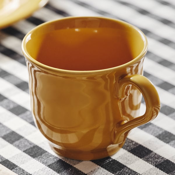 Gold mug on striped tablecloth, smooth surface, robust design.