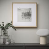 Framed landscape art on wall with vases and lamp.