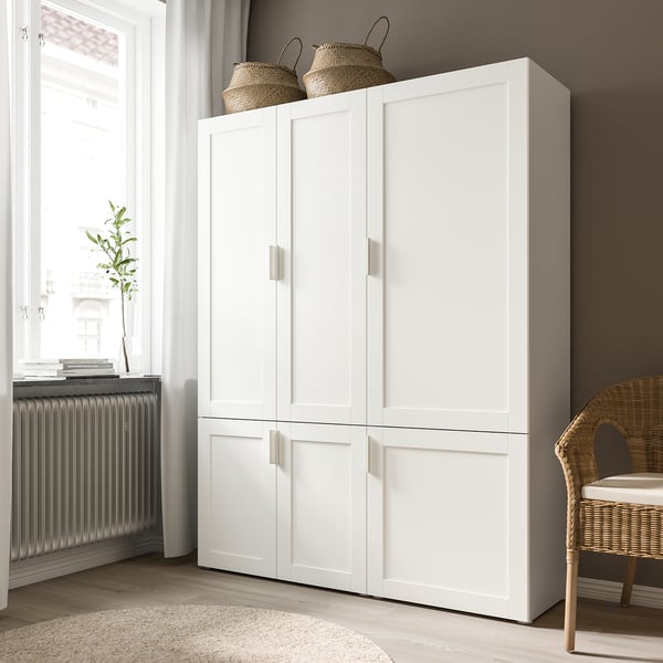 White SANNIDAL wardrobe doors with two baskets on top, next to a wicker chair.