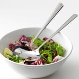 A bowl of mixed greens with salad servers; stainless steel utensils designed for durability and easy cleaning.