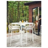 Outdoor patio sgerön white metal bar set with four stools, cushioned seats, and a glass table. Surrounded by woods, a person enters a building.