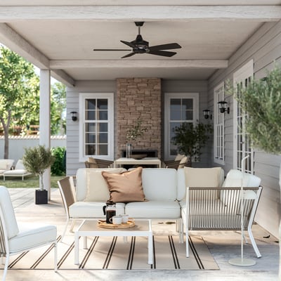 Compact patio set with cream cushions, glass table, wall lights, and ceiling fan.