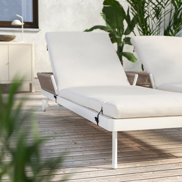 Modern white outdoor lounge chair with adjustable back, light beige cushion, powder-coated steel frame, on wooden deck.