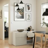 Modern living room: glossy cabinet, art, wooden chairs, kettle.