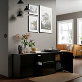 Modern living room with black glossy console, flowers, and art.