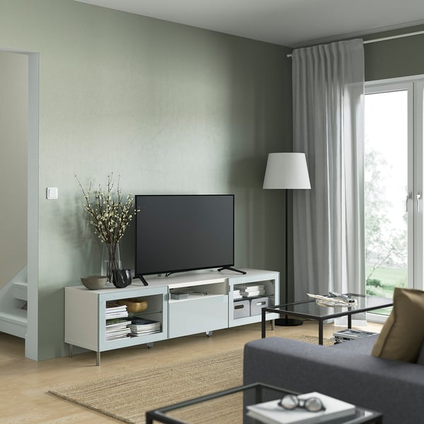 Living room with large tv, grey sofa, and glass coffee table against green wall.