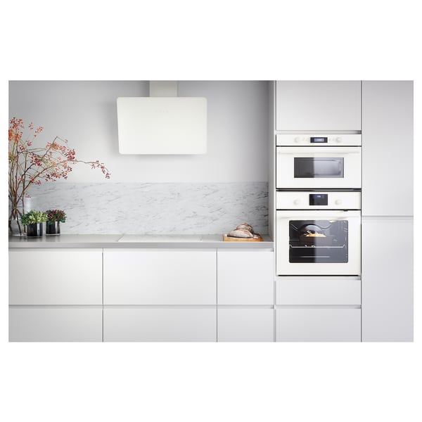 Modern white kitchen with minimalist design, peel-and-stick walls, dual ovens, marble counters, and contemporary accessories.
