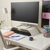 White monitor stand elevates screen, supports keyboard & offers storage. Colorful accessories enhance comfort & organization.