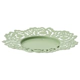 A round green metal candle dish with a delicate floral cutout design.