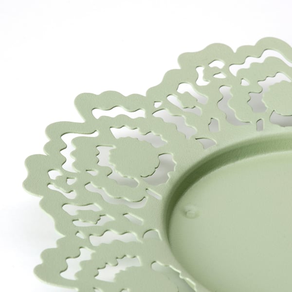 Light green metal candle dish with intricate, laser-cut floral patterns for a modern twist on traditional craftsmanship.