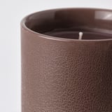 Close-up of dark brown textured candle, showing intricate pattern and wick, highlighting its artisanal quality.