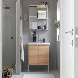 Small modern wooden vanity with sink and mirror, placed between shower and door, with black accents and white countertop.