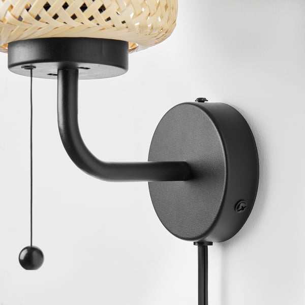 Handcrafted bamboo wall lamp with clean design, mounted on matte black base and adjustable arm. Well-made, stylish home decor.