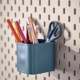 Blue SKÅDIS organizer on pegboard holds pens and scissors, keeping items handy and organized.
