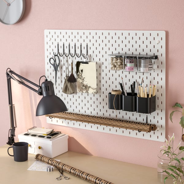 Wall-mounted pegboard with hooks, containers, and shelves, holding office supplies and tools neatly.