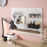 Wall-mounted pegboard with hooks, containers, and shelves, holding office supplies and tools neatly.