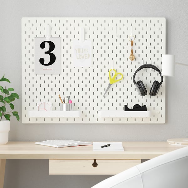 SKÅDIS pegboard with accessories on wall above desk.