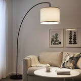 Cozy living room with SKAFTET lamp, beige couch, throw & books.