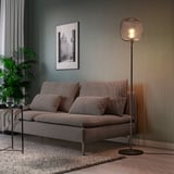 Modern living room with gray mid-century sofa, tall floor lamp, art, and plant. Floor lamp is SKAFTET, steel base, tall, and narrow.