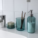 Bathroom set including soap dispenser, toothbrush holder, and tray displayed on a white countertop. The items are teal and organized neatly.