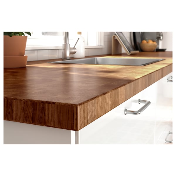 Modern kitchen counter with stainless steel sink, featuring SKOGSÅ wooden worktop in brown with silver handles.