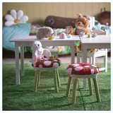 Polka-dot cushions on stools with stuffed animals and teacups, perfect for kids play in whimsical forest setting.