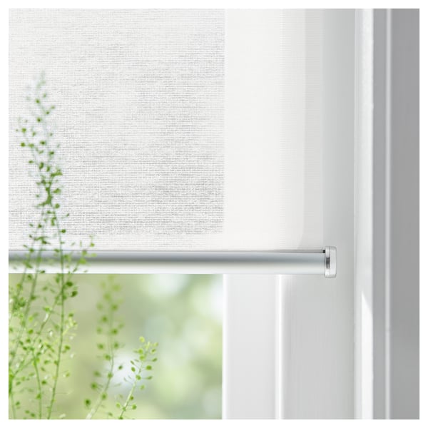 A white cordless roller blind, SKOGSKLÖVER, partially drawn, filtering light and offering a sense of privacy.