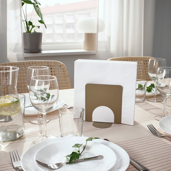 Table set with glasses, plates, and cutlery. Napkins neatly held in a holder.
