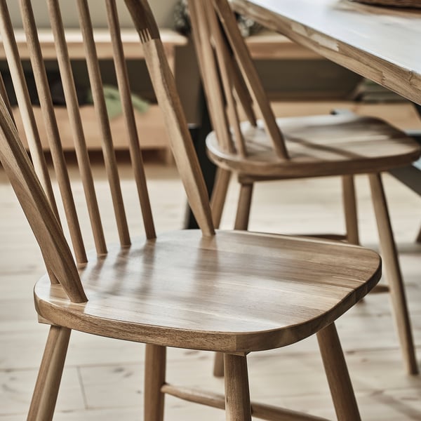 SKOGSTA chairs: light brown, wooden, arched back, spindle design. Slim, fits well in spaces.