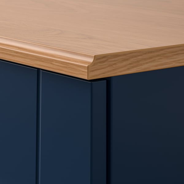 Close-up of SKRUVBY cabinet edge showing smooth, oak-finished top and dark blue sides.