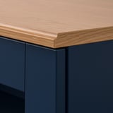 Close-up of SKRUVBY furnitures stylish, warm oak top with sleek, profiled edges and dark blue base unit, showing high-quality craftsmanship.